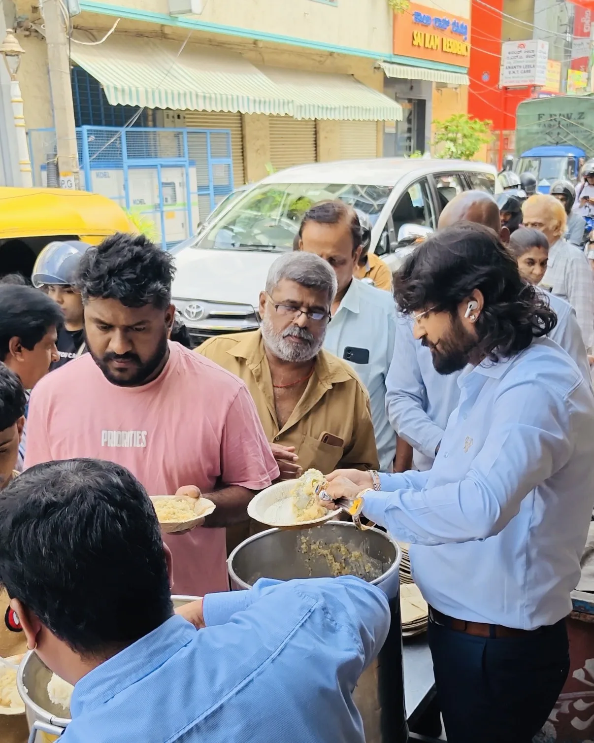 Dr. Chetan Kumar Mehta serving Anna Danam meals to a crowd near a temple, Bengaluru
